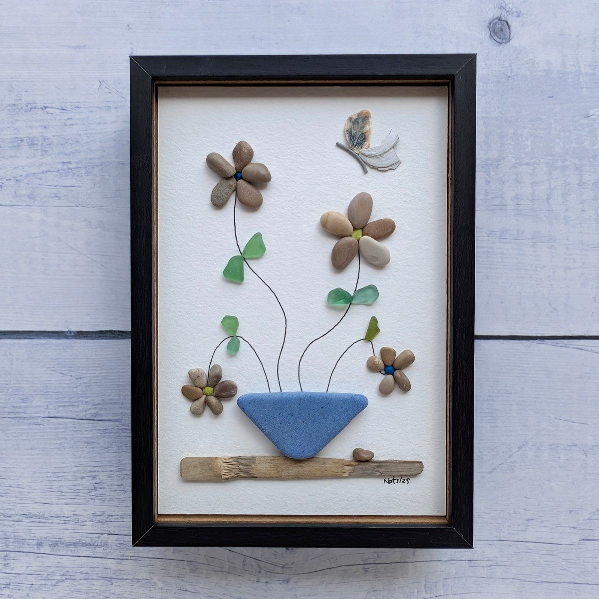 Cuadro Florecitas de arte reciclado, vista frontal, colgado en pared, vertical, marco negro.