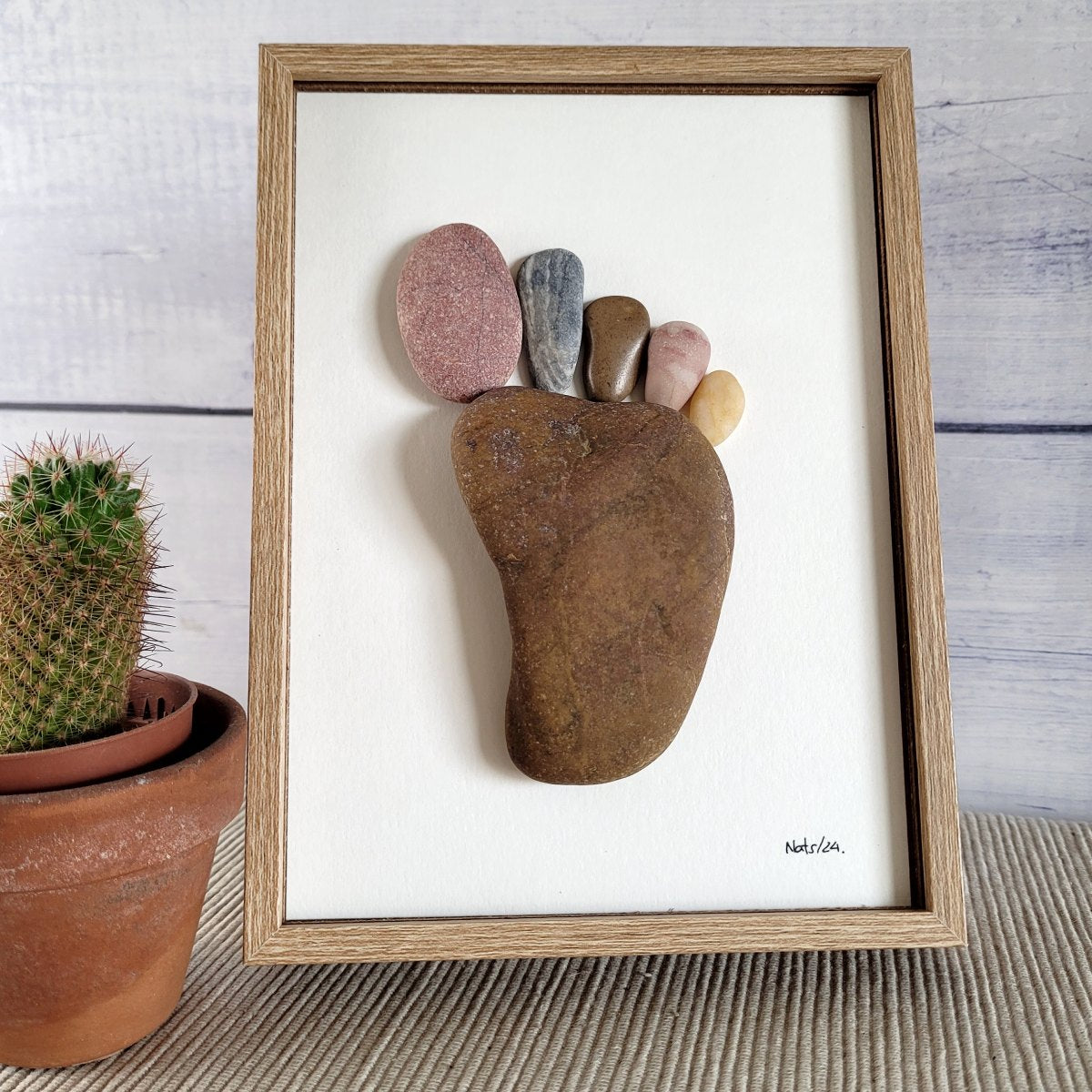 Cuadro Huella del Pie, artesanía hecha con piedras, sobremesa, vertical, 13 x 18 cm, marco marrón.