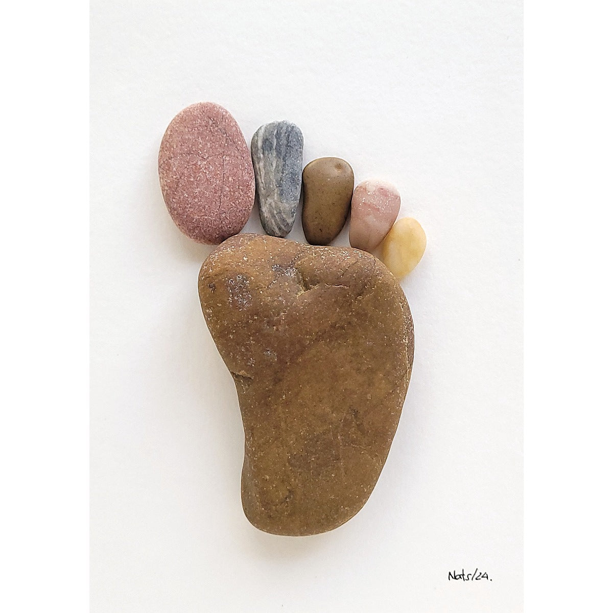 Cuadro Huella del Pie, detalle de guijarros de playa en primer plano, sobre fondo blanco.