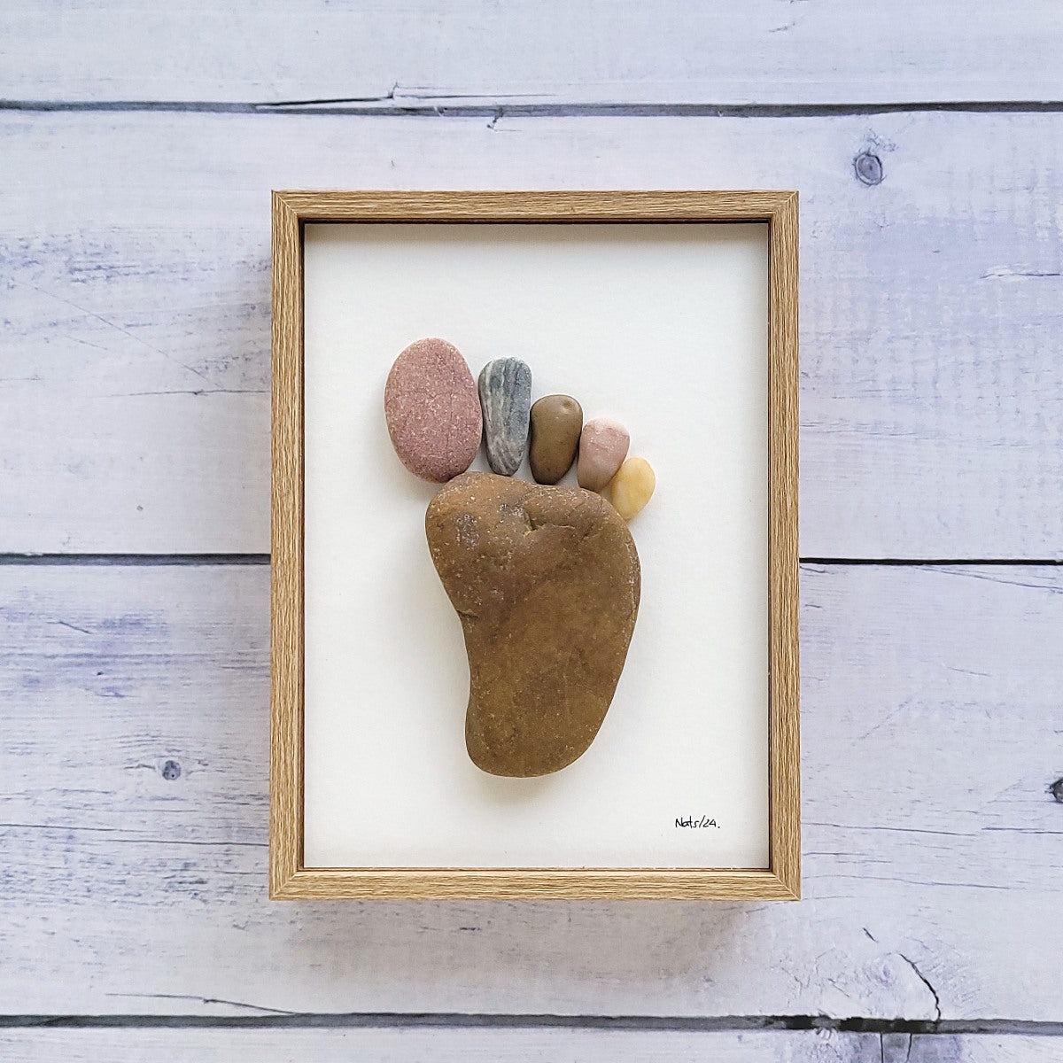 Cuadro Huella del Pie, arte sostenible, vista frontal con marco marrón, vertical, colgado en pared.
