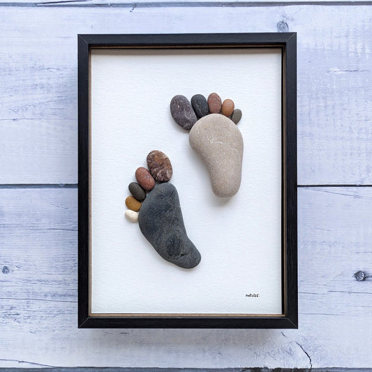 Cuadro Huellas, arte sostenible, vista frontal con marco negro, vertical, colgado en pared.
