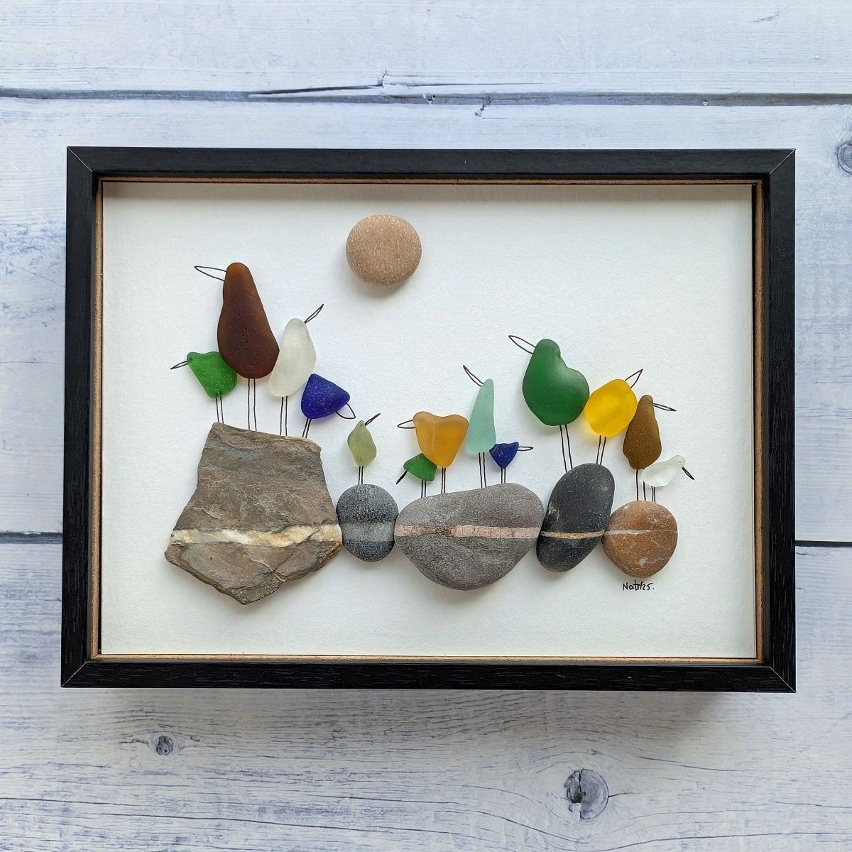 Cuadro On the Rocks, arte reciclado, vista frontal, marco negro, colgado en pared.
