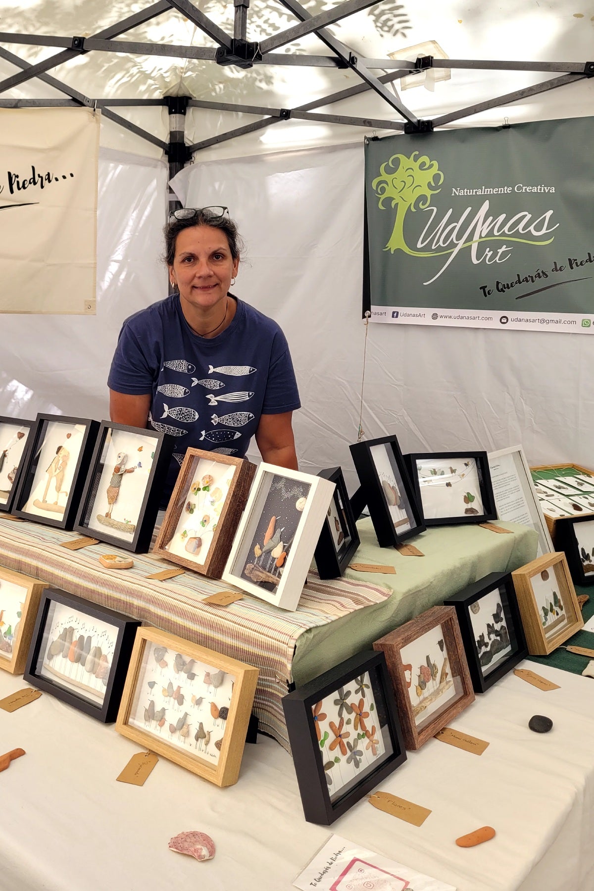 Banner para móvil UdanasArt, Natalia con sus cuadros y obras terminadas en feria de artistas en Barcelona.